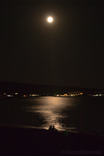 The dark sea lit by full moon, young couple feels the night